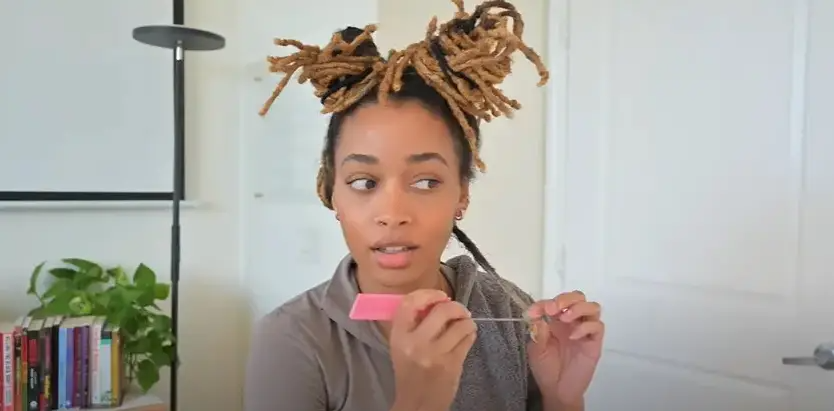 A woman combing out her locs | Source: YouTube/WestIndieRay